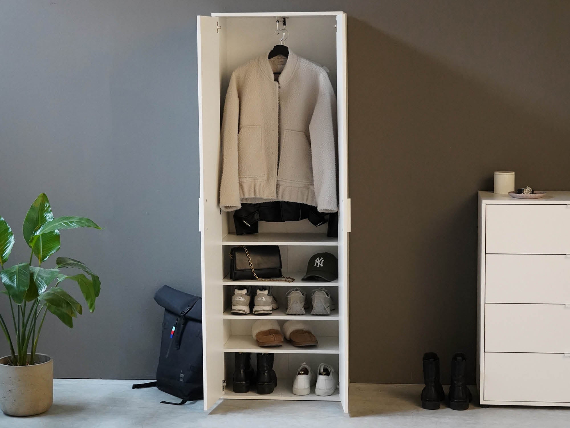 Garderobenschrank mit Kleidung und Schuhen gefüllt in Weiß